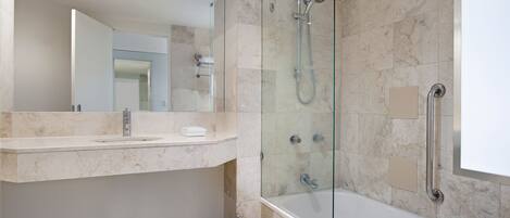 Un baño moderno con ducha de vidrio, un lavamanos blanco y un espejo grande.