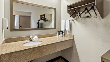 Un baño con lavamanos de granito, un espejo, un perchero para toallas y una repisa de madera.