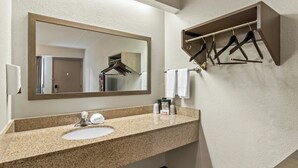 A bathroom with a granite countertop sink, a mirror, a towel rack, and a wooden shelf. - Red Roof Inn Dayton North Airport (Dayton)
