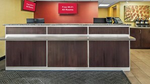 A reception desk with a flat-screen TV displaying 'Free Wi-Fi All Rooms,' a coffee machine, and a microwave. - Red Roof Inn Dayton North Airport (Dayton)
