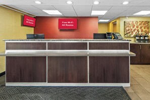 A reception desk with a flat-screen TV displaying 'Free Wi-Fi All Rooms,' a coffee machine, and a microwave. - Red Roof Inn Dayton North Airport (Dayton)