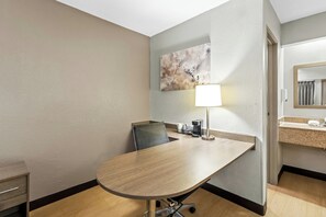 A hotel room with a conference table, a chair, a lamp, a coffee maker, a sink, and a mirror. - Red Roof Inn Dayton North Airport (Dayton)