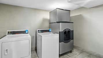 Une buanderie équipée d’un lave-linge à chargement frontal, d’un sèche-linge à chargement par le haut et d’un distributeur d’eau.