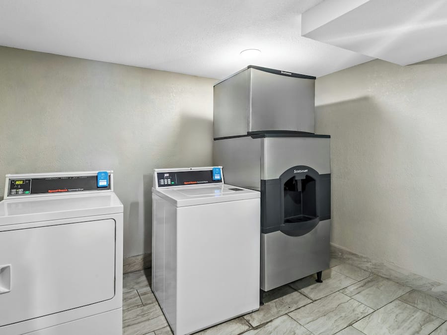 A laundry room with a front-loading washer, a top-loading dryer, and a water dispenser.