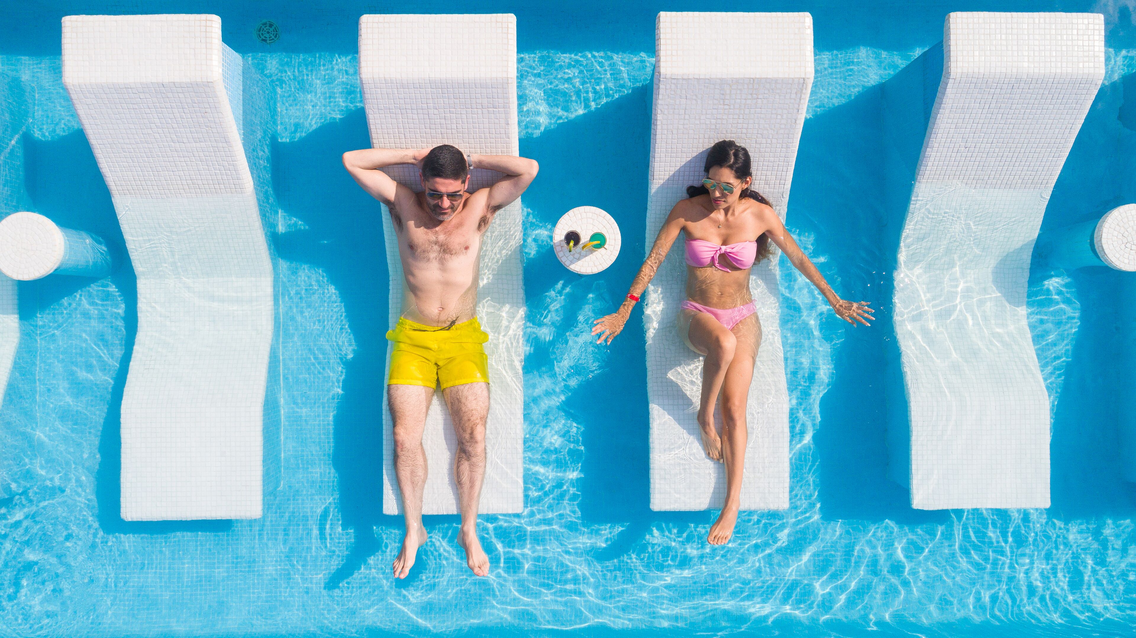 Una piscina con dos sillas de descanso y una pequeña mesa redonda.