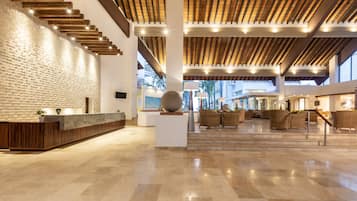 Un vestíbulo amplio con mostrador de recepción, zona de estar y vistas al exterior.