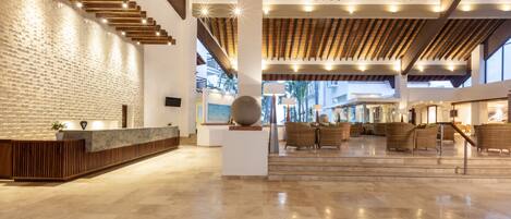 Un vestíbulo amplio con mostrador de recepción, zona de estar y vistas al exterior.
