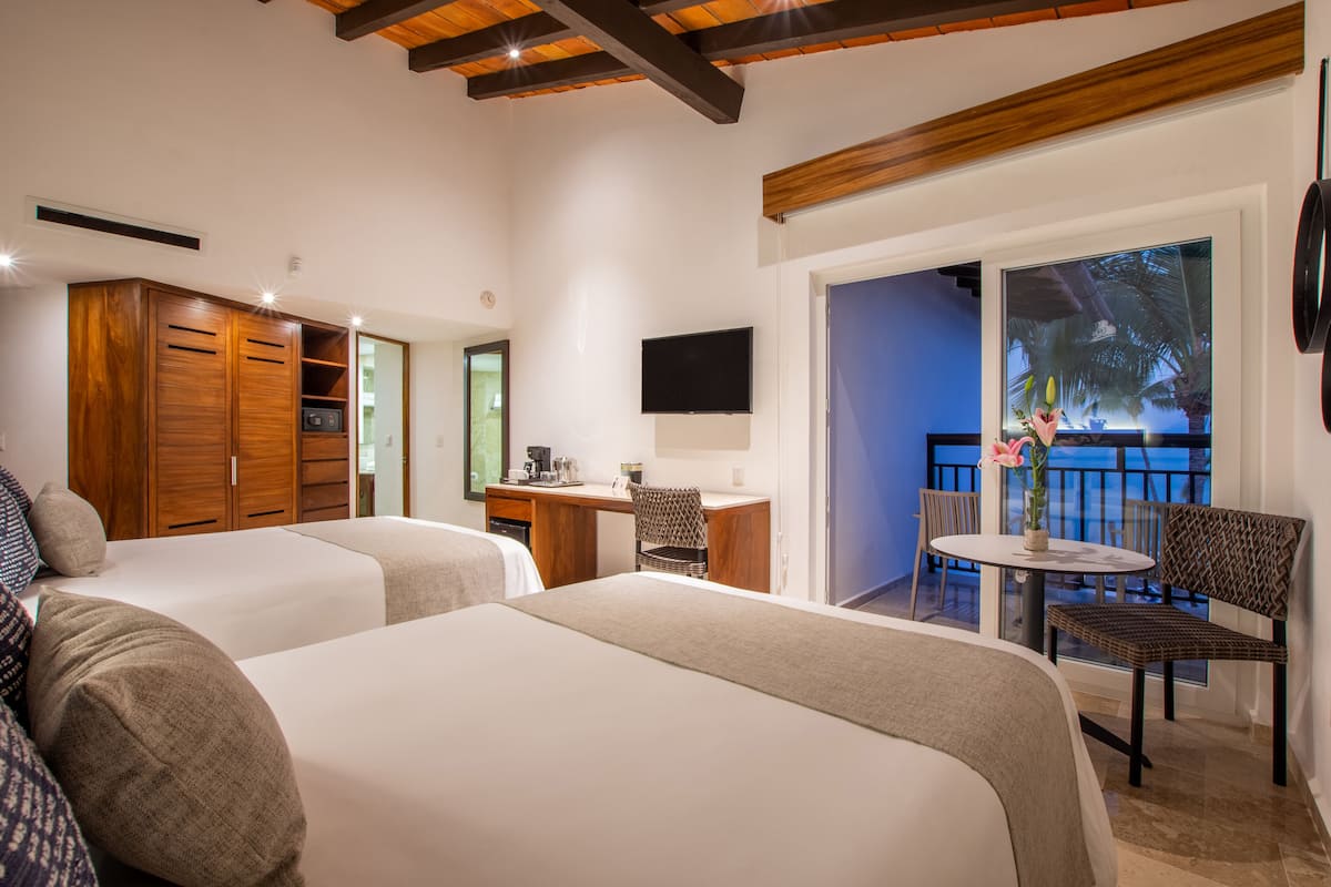 Une chambre d’hôtel avec deux lits, un bureau, une chaise, une télévision et un balcon avec vue.