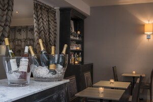A bar area with two ice buckets containing champagne bottles, a marble countertop, and a dimly lit ambiance with candles.