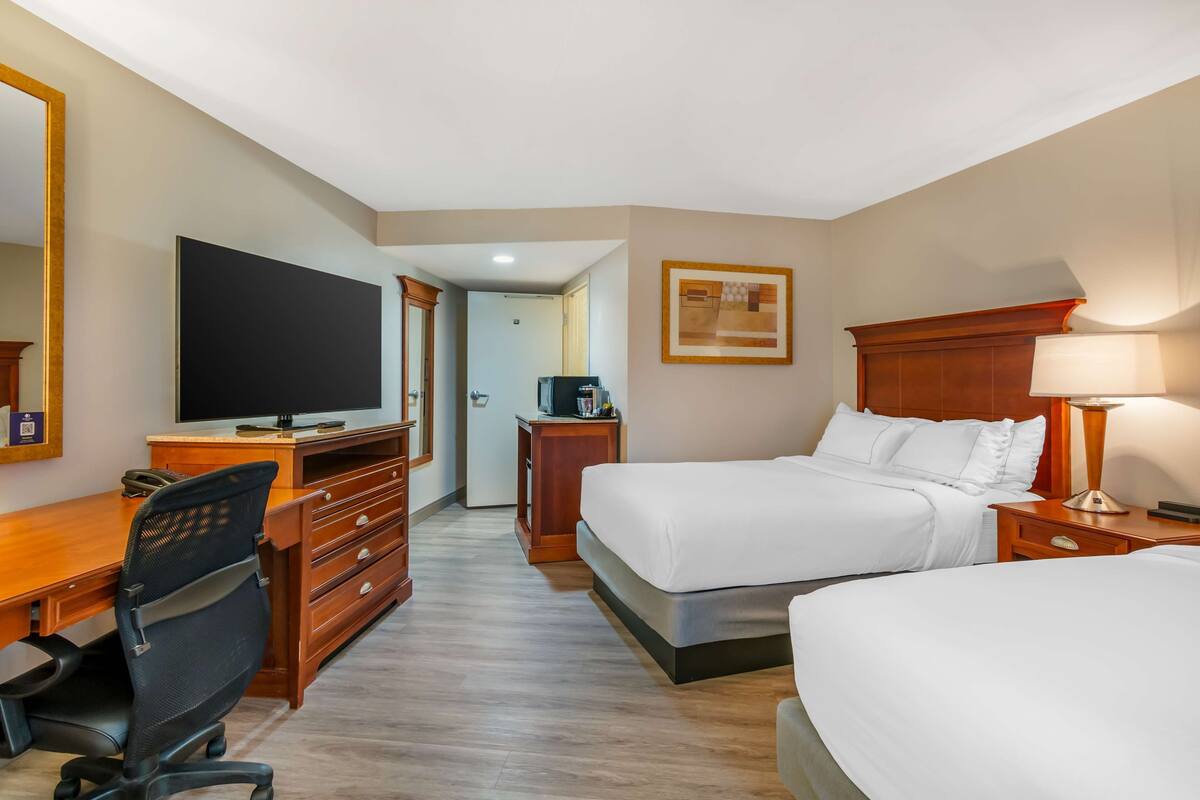 Ein Hotelzimmer mit einem Bett, einem Schreibtisch mit Stuhl, einem Fernseher und einer Lampe.