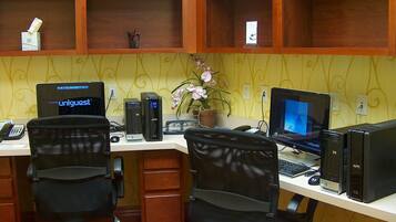 A workspace with two desks, each with a computer, a chair, and a telephone.