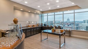 Ett modernt kök med ett stort fönster, en kaffestation och utsikt över stadsbilden.