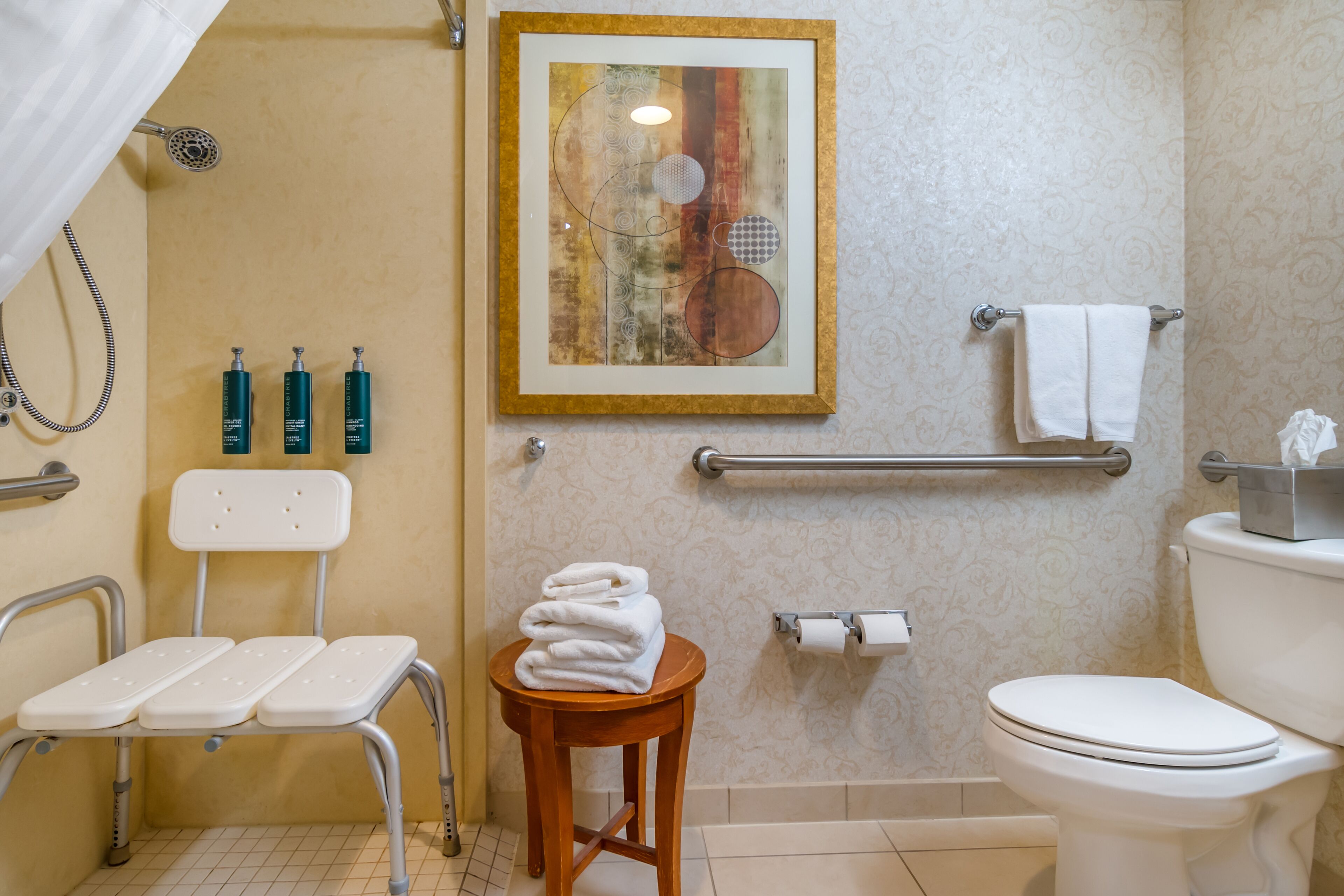 Une salle de bain avec une douche, des toilettes et une petite table sur laquelle sont posées des serviettes.
