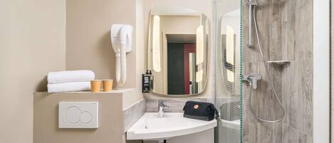 A modern bathroom with a sink, mirror, shower, and toilet.