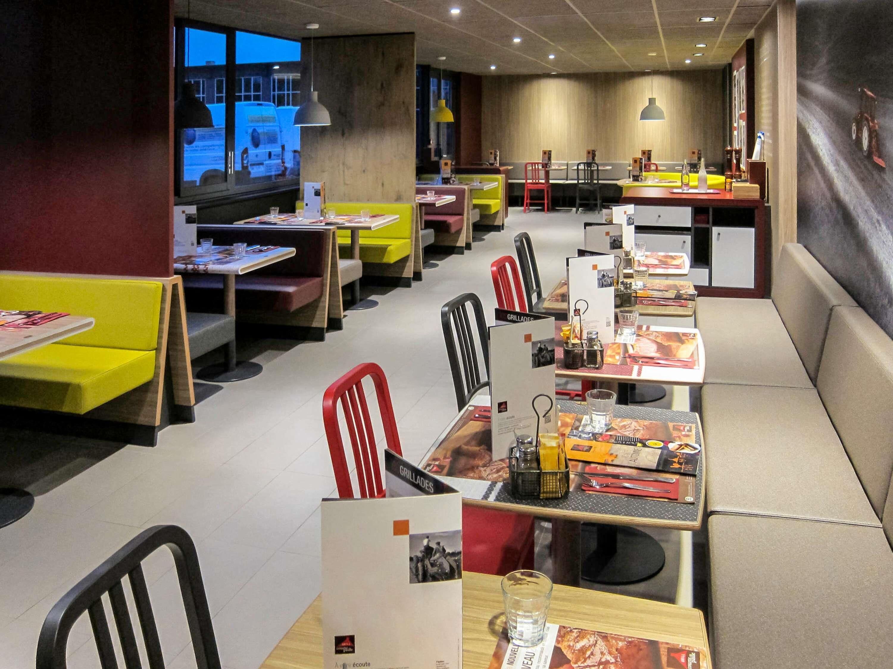 A restaurant with booths and tables, some with attached chairs.