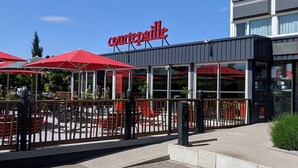 A Courtepaille restaurant with outdoor seating, red umbrellas, and a modern building facade. - ibis Lyon Villefranche sur Saone (Limas)
