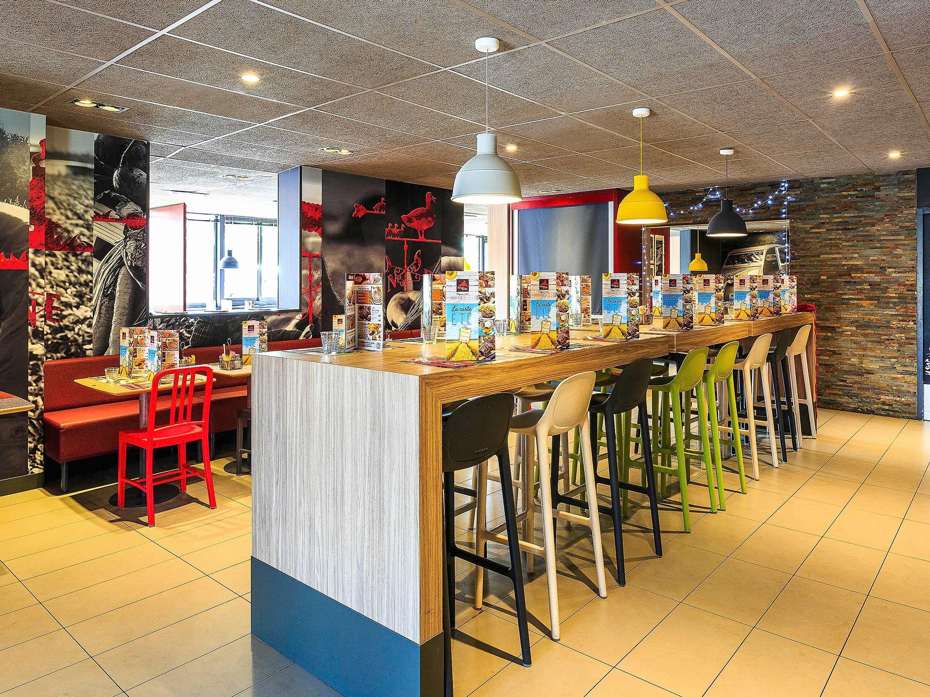 Un restaurant avec un long comptoir, des tabourets et un menu affiché.