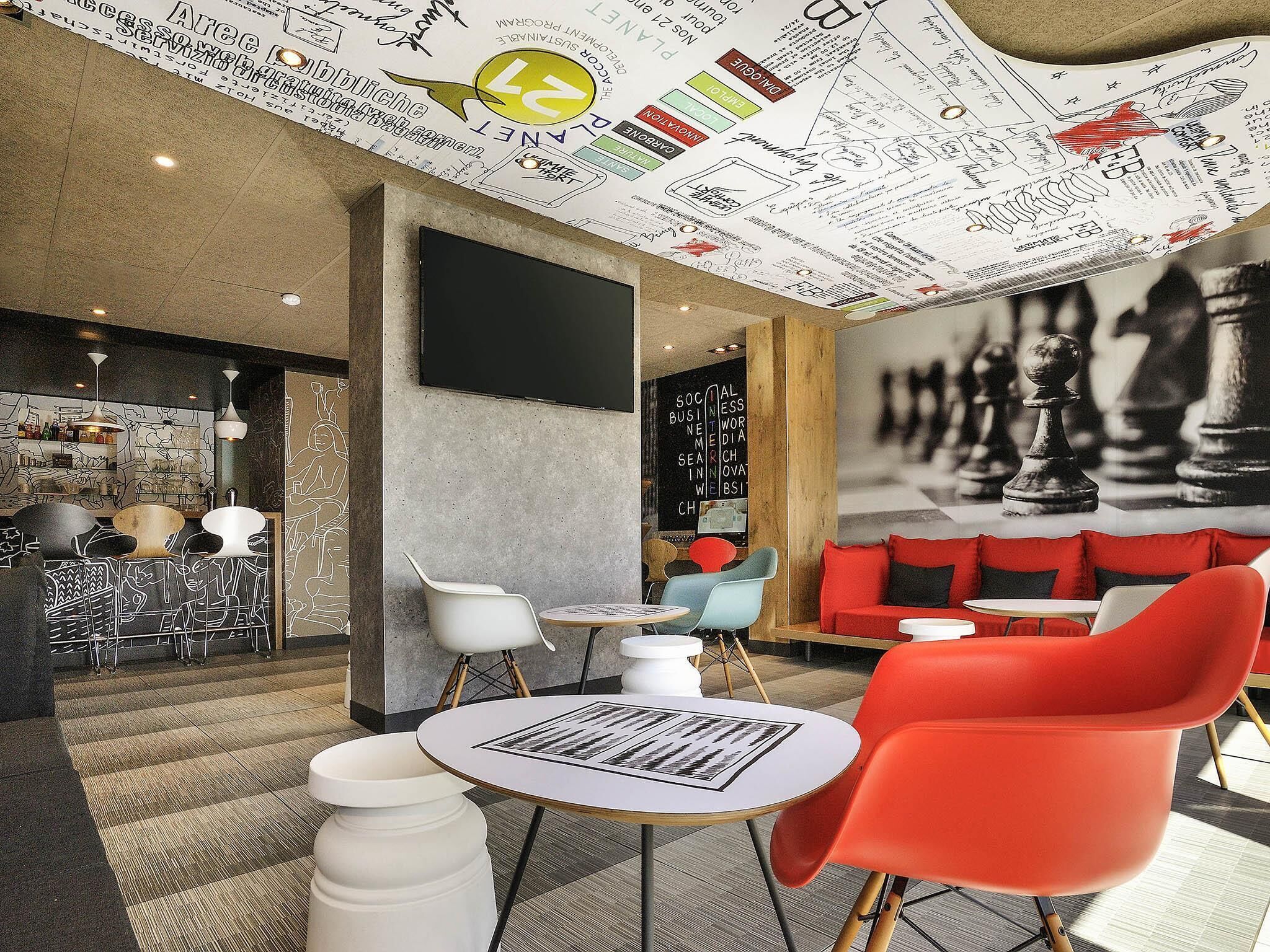 Un interior moderno con un mural de ajedrez, una zona de bar y diferentes disposiciones de asientos.