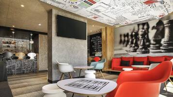 Un interior moderno con un mural de ajedrez, una zona de bar y diferentes disposiciones de asientos.
