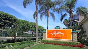 A Tropicana Inn sign with a clear view of the surrounding greenery and palm trees. - Tropicana Inn and Suites (Anaheim)