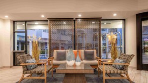 A modern lobby with a sofa set, two chairs, a coffee table, and decorative vases. - Tropicana Inn and Suites (Anaheim)