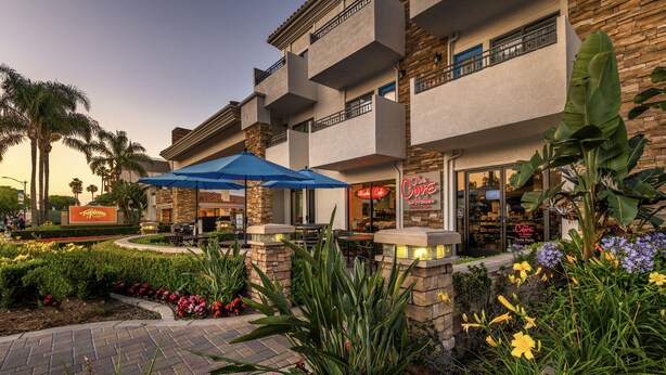 A hotel with outdoor seating, a patio area, and a flower garden. - Tropicana Inn and Suites (Anaheim)