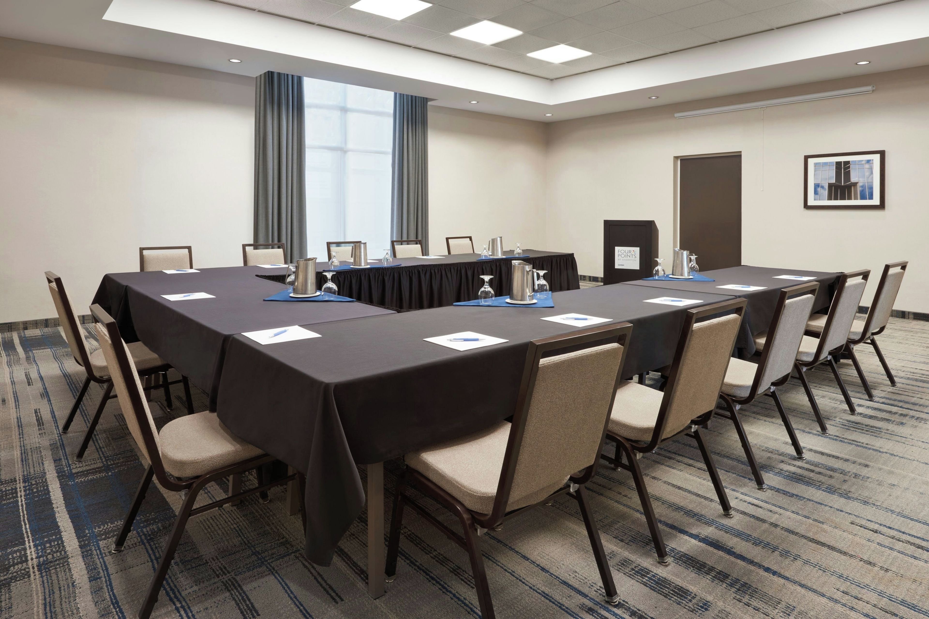 A conference room with a long table, chairs, and a podium.