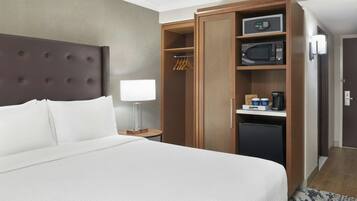A hotel room with a large bed, a wardrobe, a microwave, and a coffee machine.