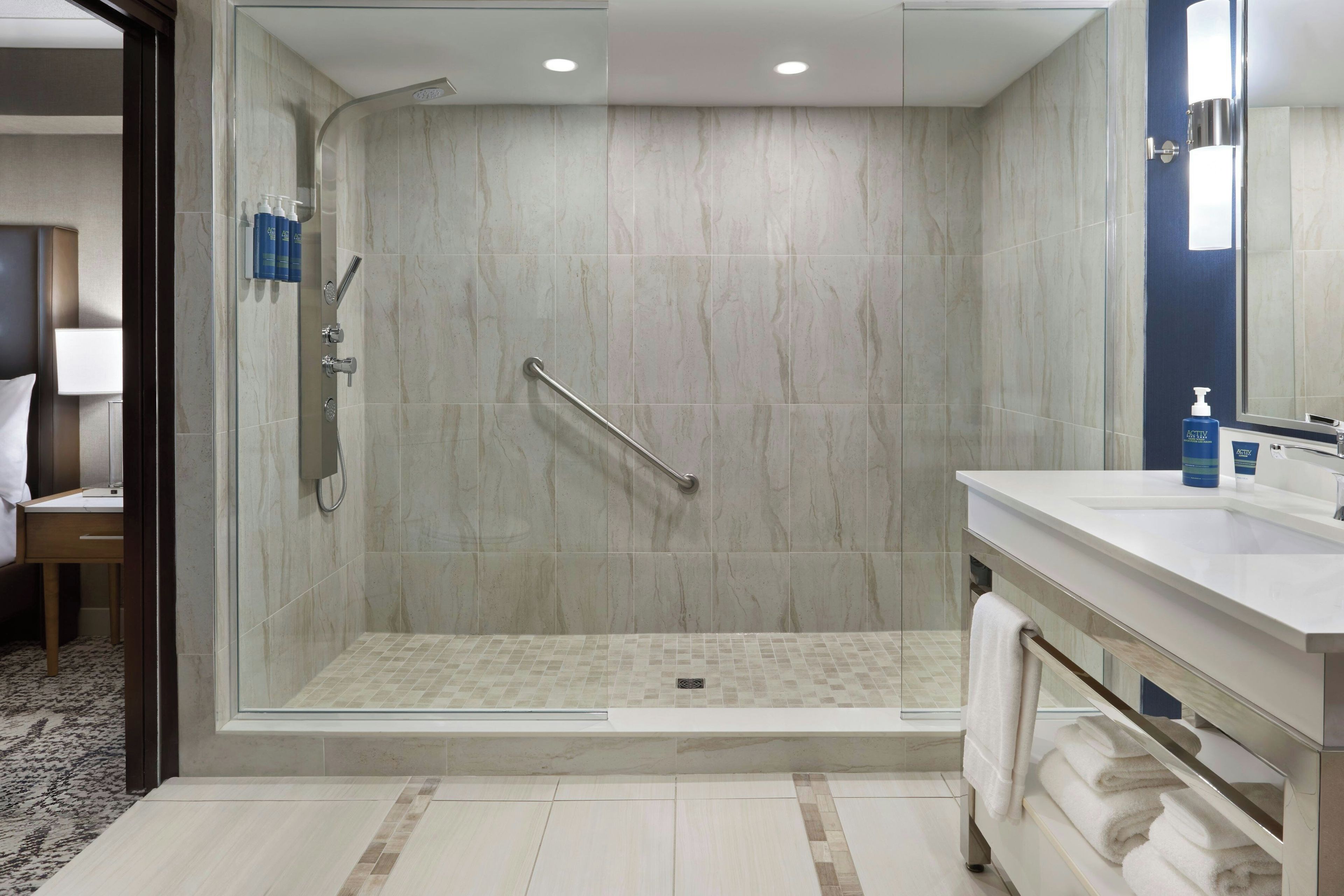 A modern bathroom with a glass-enclosed shower, a vanity with a sink, and a towel rack.