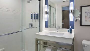 A modern bathroom with a glass shower enclosure, a white sink with a mirror, and a toilet.