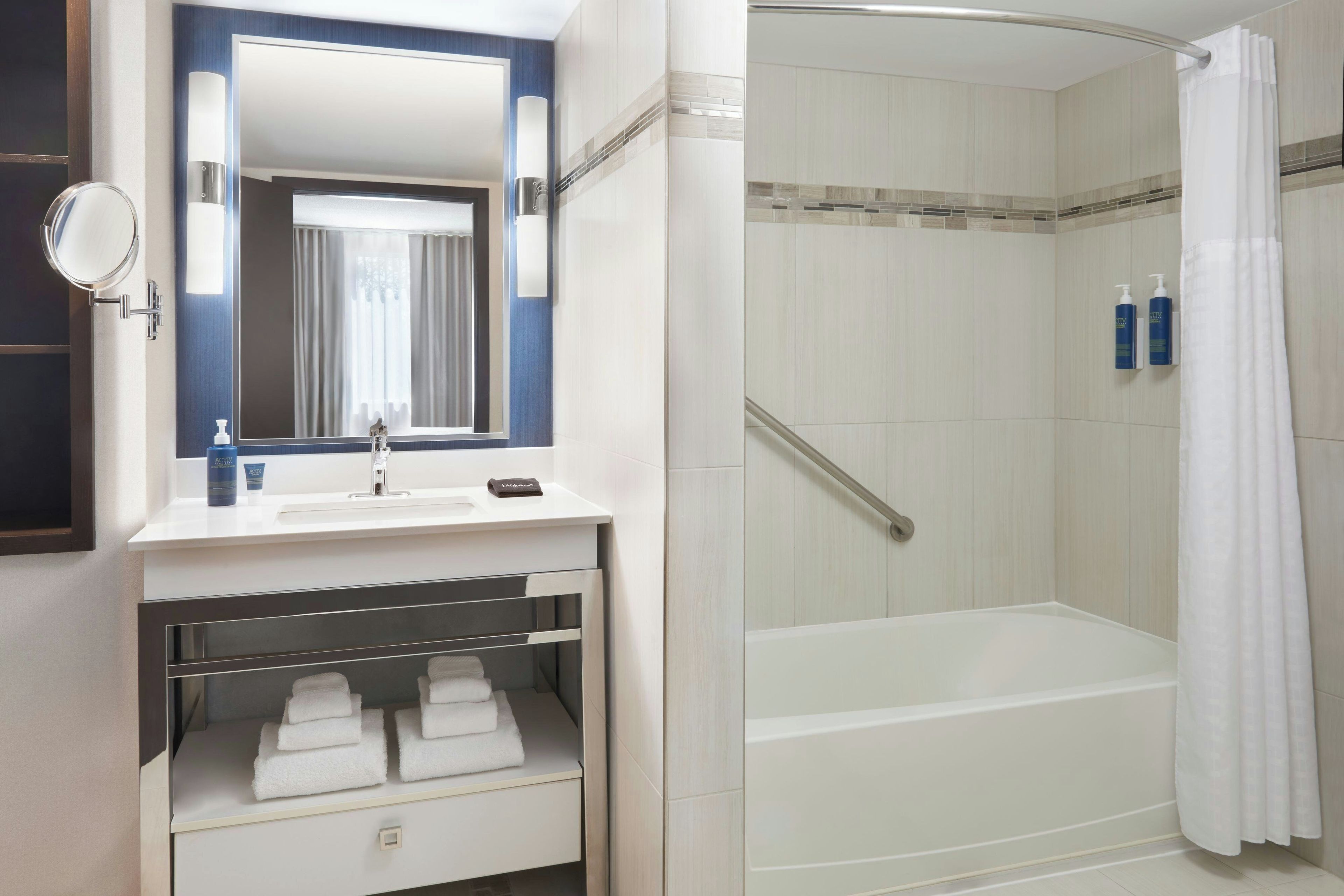 Une salle de bain moderne avec un lavabo intégré, un miroir, une douche avec une porte en verre et un porte-serviettes.