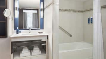 Un baño moderno con lavamanos integrado, espejo, ducha con puerta de cristal y barra para toallas.