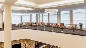 Un hall d’entrée spacieux avec un plafond haut, de nombreux espaces aménagés pour s’asseoir et de grandes fenêtres.