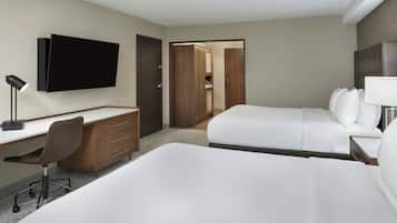 Una habitación de hotel con cama, escritorio, silla, televisión y armario.