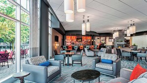 Un vaste espace de détente avec des sièges confortables, un bar et de grandes fenêtres offrant une vue sur l’extérieur.