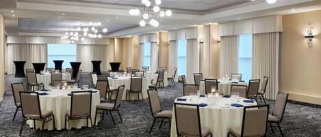 A conference room with round tables, chairs, and a chandelier.