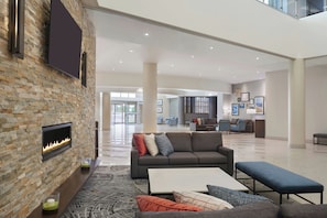 A spacious lobby with a stone wall fireplace, comfortable seating, and a modern design. - Four Points by Sheraton London (London)