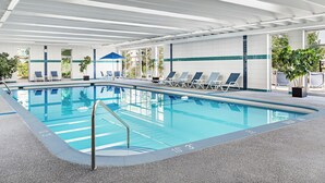 Une piscine intérieure avec des couloirs bien délimités, des chaises longues et un espace abrité sous une tonnelle bleue.