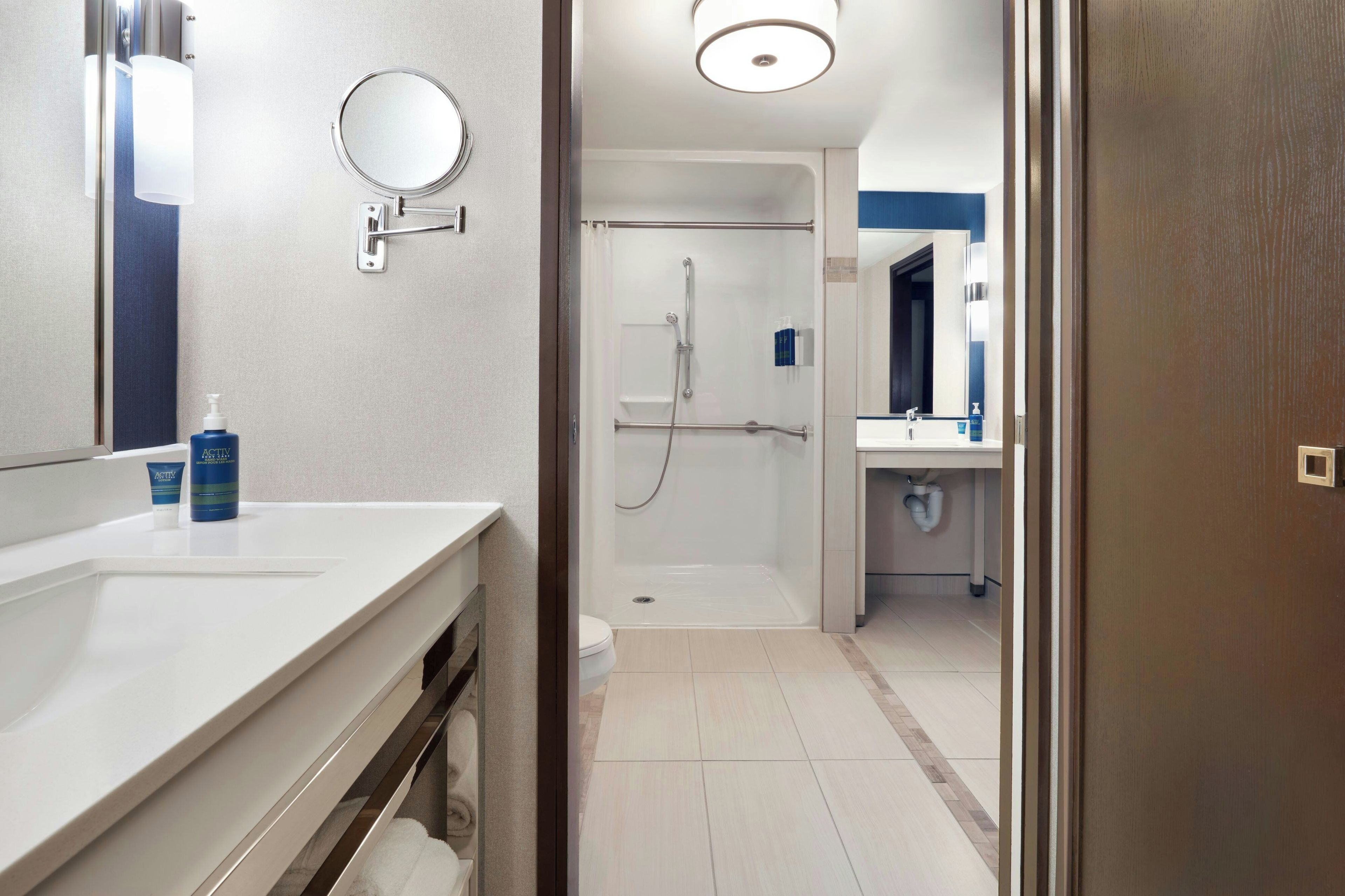 Een moderne badkamer met een wit wastafelmeubel, een spiegel en een douchegedeelte.