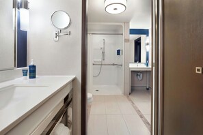 Un baño moderno con un lavamanos blanco, un espejo y una zona de ducha.