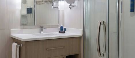 A modern bathroom with a glass-enclosed shower, a vanity with a mirror, and a towel rack.