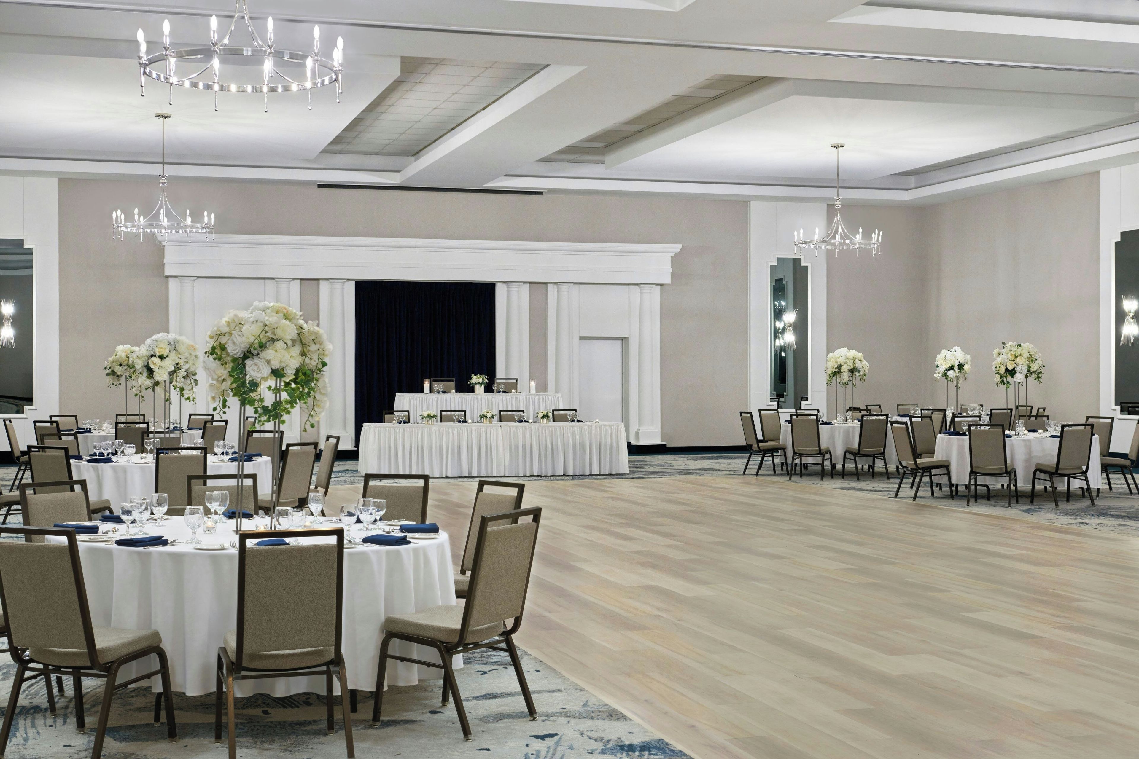 Un amplio salón de banquetes con mesas redondas, sillas y candelabros.