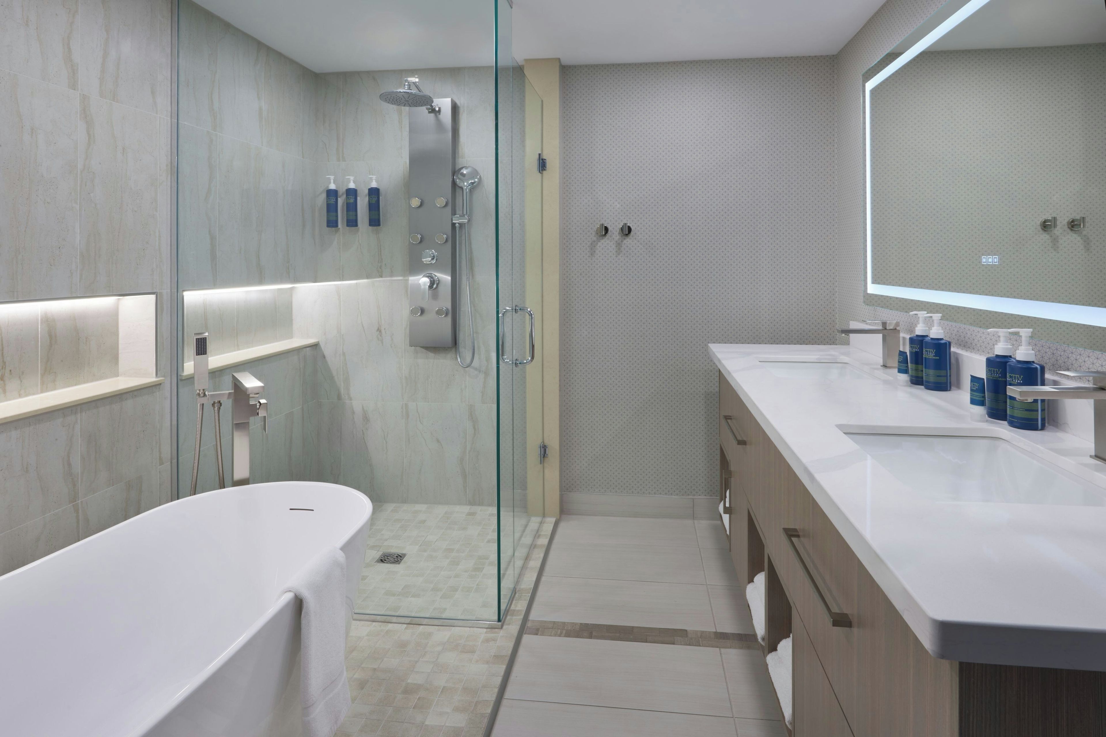 A modern bathroom with a glass-enclosed shower, a freestanding bathtub, and a vanity with a large mirror.
