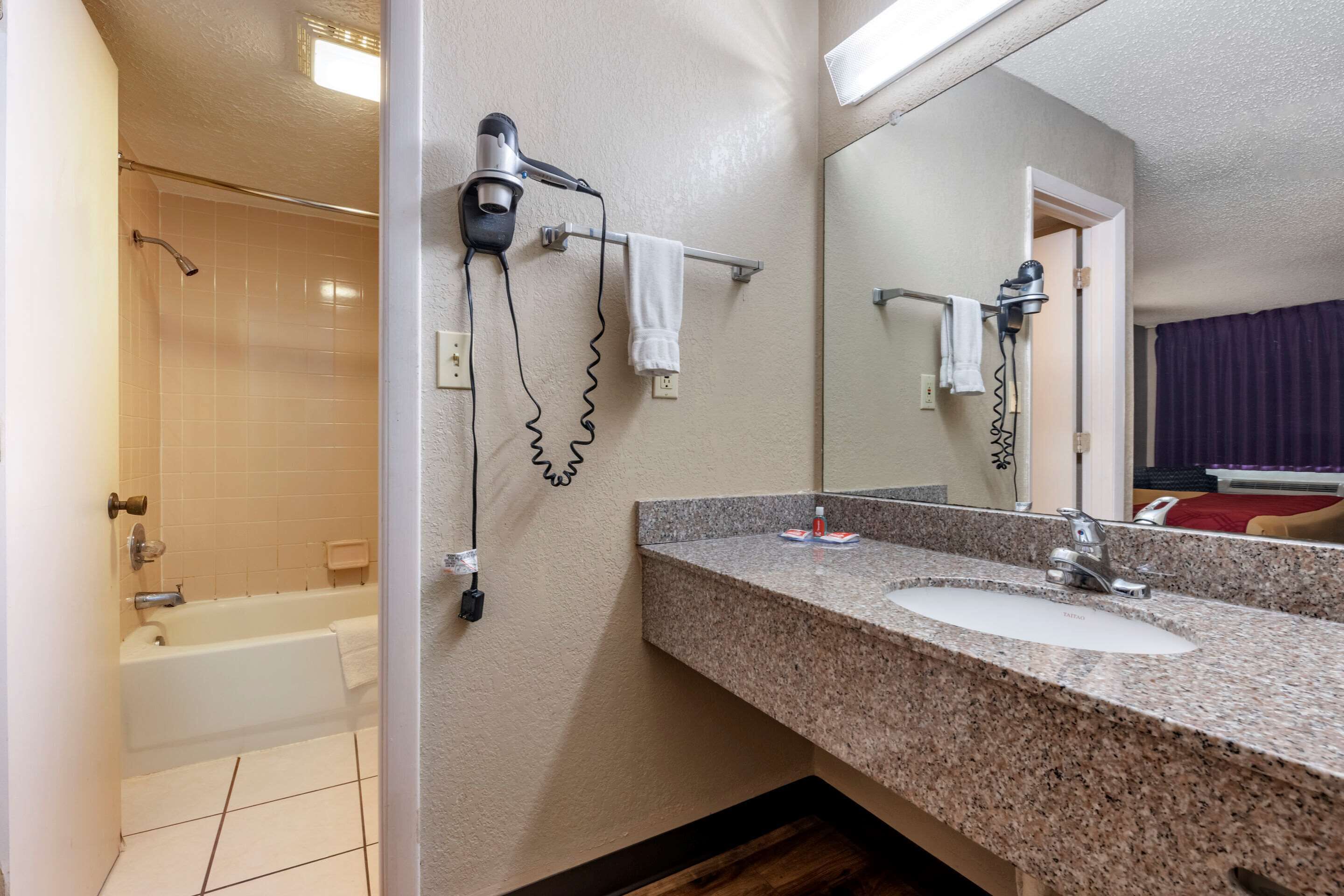 Un baño con lavabo, espejo, toallero y secador de pelo.