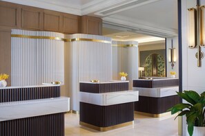 A reception area with three counters, each with a white marble top and a dark base. There are decorative vases with yellow flowers on the counters.