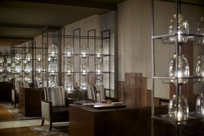 A hotel lobby with seating areas, a reception desk, and a wall decorated with glass jars and lights.