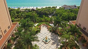 A resort with a central courtyard, palm trees, and a view of the beach and ocean. - The Ritz-Carlton, Naples (Naples)