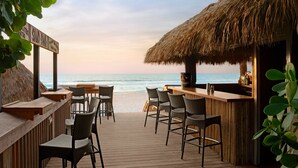 A beachside bar with wicker chairs and a thatched roof, overlooking the ocean. - The Ritz-Carlton, Naples (Naples)