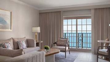 Un salon spacieux doté d’une grande fenêtre donnant sur la mer, d’un canapé confortable, d’une table basse et d’un fauteuil.