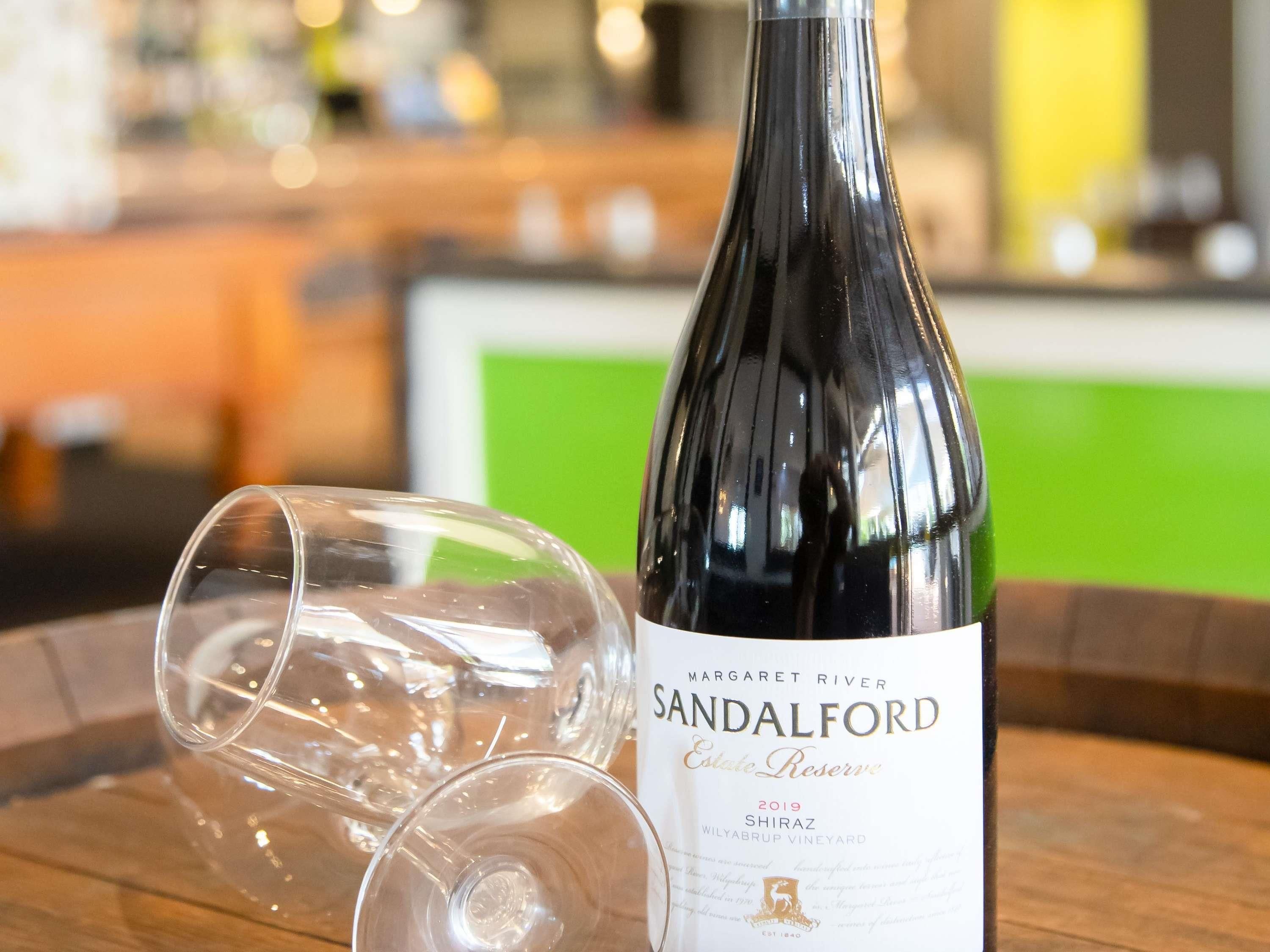 A bottle of Margaret River Sandalford Estate Reserve 2019 Shiraz wine on a wooden tray with a wine glass.